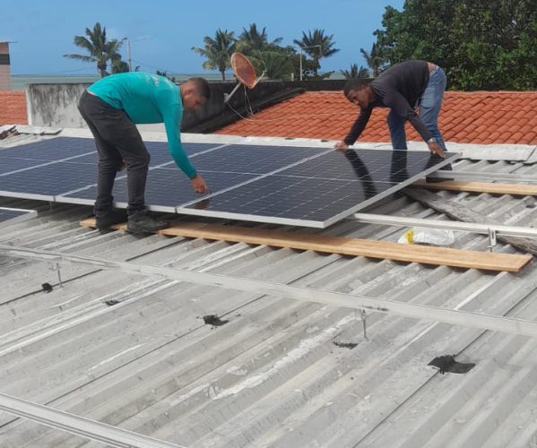 Técnicos da Usina dda Energia instalando painéis solares sobre um telhado de fibrocimento